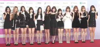 Image of Iz*One members smiling and wearing elegant black and white short dresses