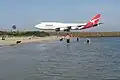 Qantas jet on taxiway with aircraft viewing area and Botany Bay beach in foreground