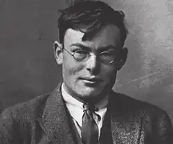 Ramsey seated, wearing a suit and looking toward the camera