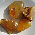 Tumble polished translucent agate pebbles showing gold, red and white colors.