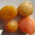 Peach reds and yellows with threadlike mossy and cell-like formations in semi-smooth tumbled agate pebbles.