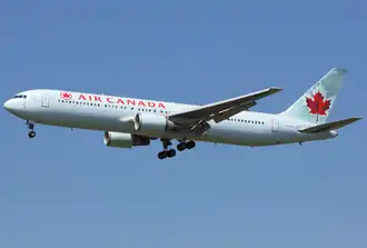 A side/underneath view of a Boeing 767-300 in Delta Air Lines' white, blue, and red color during climbout. The main undercarriage doors are retracting.