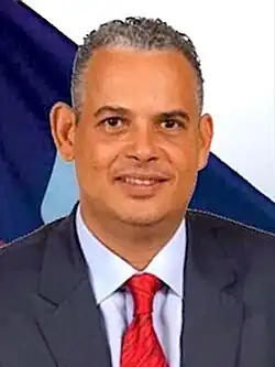Headshot of Fils-Aimé looking down and speaking into an iPhone