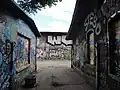 The alleyway is dark and grey, leading across a path.