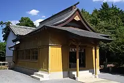 社殿拝殿（黄色い壁の部分）から続く屋根覆い（白い壁の部分）により本殿は雨風から保護されている。