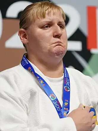 Image of Harnyk with a medal around her neck and her right hand on her hearth
