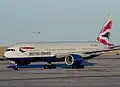 A British Airways Boeing 777 taxiing and a Frontier Airlines Airbus A319 taking off at the airport.
