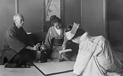 A black and white photo of a Japanese bride in traditional attire greeting her elders