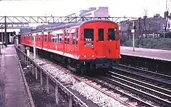 A three-quarter photograph of a red train with sliding doors and flared sides.