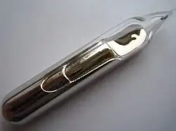 Some pale gold metal, with a liquid-like texture and lustre, sealed in a glass ampoule