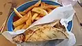 Chicken souvlaki pita served with French fries in a restaurant in the United States.