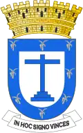 Silver leaves around the inside perimeter of a heraldic shield, in the center a blue cross and five golden towers atop
