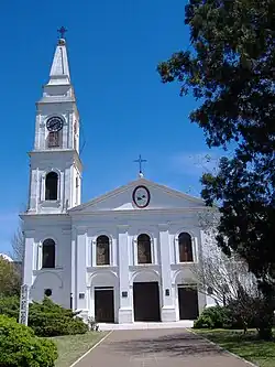 Two story white church with three story clock tower on the left