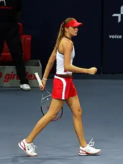 Daniela Hantuchova in a white top and red & white shorts, red cap, walking on a blue indoor surface