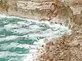 A rough Dead Sea, with salt deposits on cliffs