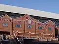 Brick facade of a stadium with a mosaic with a claret background and Aston Villa in gold writing.