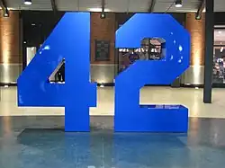 An eight-foot blue sculpture of a stylized uniform number, 42, set atop a polished interior walkway