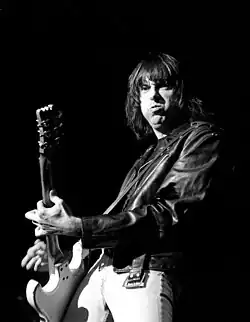 A punk playing guitar on a stage.