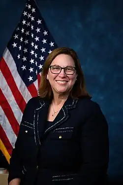 Official House portrait of Johnson smiling in front of the U.S. flag, wearing a black jacket and silver necklace.