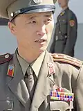 A Korean People's Army Lieutenant Colonel in the JSA. His decorations include a Kim Il Sung lapel badge, Order of the National Flag 2nd class (awarded for at least 20 years service in the Korean Workers' Party) and two Medals For Military Service.
