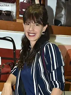 Koechlin posing for the camera in a white coat and a sheer dress