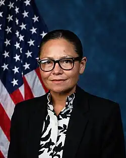 Official House portrait of King-Hinds in front of the U.S. flag, wearing a black jacket and floral black and white shirt.