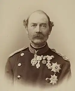 Portrait of Christian in military uniform. He places his left hand on his sword and his right hand on a table with some books.
