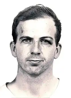 Black-and-white mug shot of Oswald standing