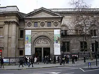 Exterior of a large building with many windows building, with people standing on its steps