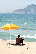 A man sitting under beach parasol.