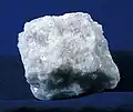 A chunk of pure white marble lies on a dark background.