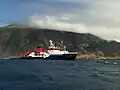 A German ship in Tristan da Cunha. In the back is Queen Mary's Peak and to the right is Edinburgh of the Seven Seas.