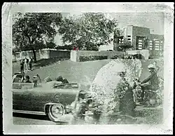 John F. Kennedy is fatally shot in the head, with Jacqueline Kennedy sitting beside him. Jacqueline can be seen turning over and looking at him at that moment.