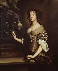 A pale, dark-eyed, black-haired young lady wears a dress with matching pearl earrings and a necklace.