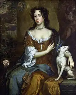 A black-haired young lady wears a brown dress with a pearl necklace.