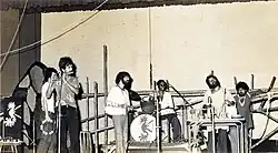 Moheener Ghoraguli in concert at Rabindra Sadan, 1979, left to right: Raja Banerjee, Pradip Chatterjee, Tapas Das, Pranab Sengupta, Gautam Chattopadhyay and Ranjon Ghoshal.  Not shown also present were Abraham Mazumder and Biswanath Chattopadhyay