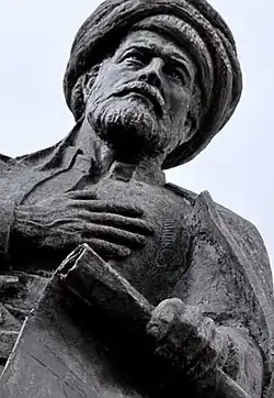 A color photograph of a black statue of a bearded and turbaned man