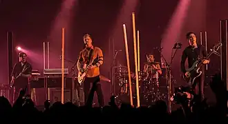 Queens of the Stone Age performing at Wembley Arena in November 2017; left to right: Dean Fertita, Josh Homme, Jon Theodore, and Michael Shuman