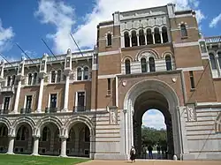 The academic seal of Rice University. A shield divided by a chevron, carrying three owls as charges, with scrollwork saying "LETTERS", "SCIENCE", "ART".