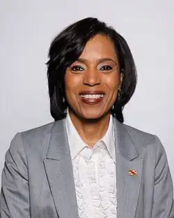 Official Senate headshot of Alsobrooks smiling on a grey background, wearing a white shirt and dark grey jacket with a Maryland flag lapel pin.