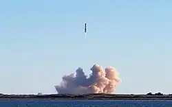 A picture of flying steel rocket with a large dust cloud below