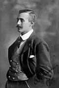 A man pictured (1901) in a three-piece suit with pocket handkerchief showing