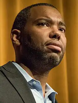 A low-level view of Coates onstage wearing a suit