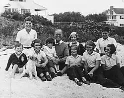 Large family gathering on a beach in front of a house