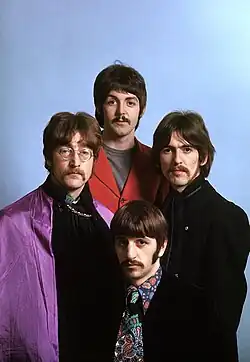 A square quartered into four head shots of young men with moptop haircuts. All four wear white shirts and dark coats.