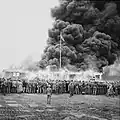 A crowd watches the last camp hut be destroyed