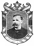 Framed portrait of a white man with an extremely bushy mustache, wearing a dark suit coat and bow tie.